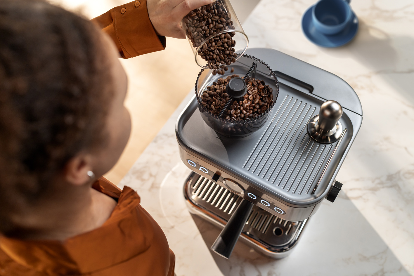 Mlada djevojka istresa zrna kave u spremnik za zrna kave aparata Philips Barista Brew